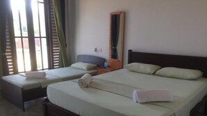 A hotel room with two single beds, a wooden headboard, a nightstand, and a mirror. - Summer Cottage (Arugam Bay)