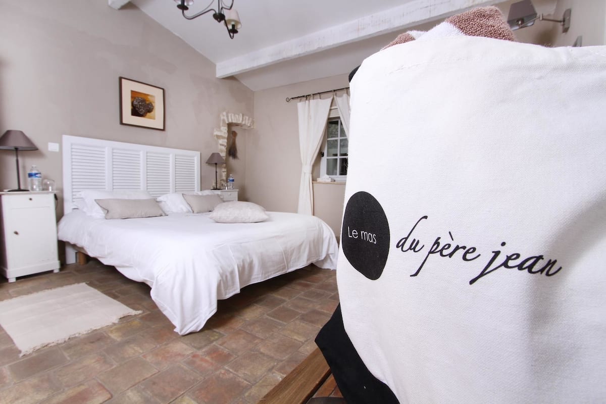 A bedroom with a bed, nightstand, lamp, and a towel with text.