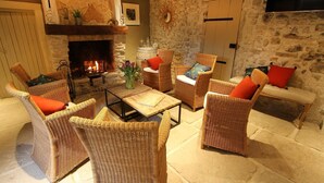 A cozy living room with wicker furniture, a stone fireplace, and a television mounted on the wall.