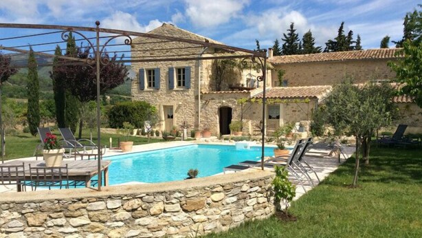 A stone villa with a swimming pool, outdoor seating, and a pergola.