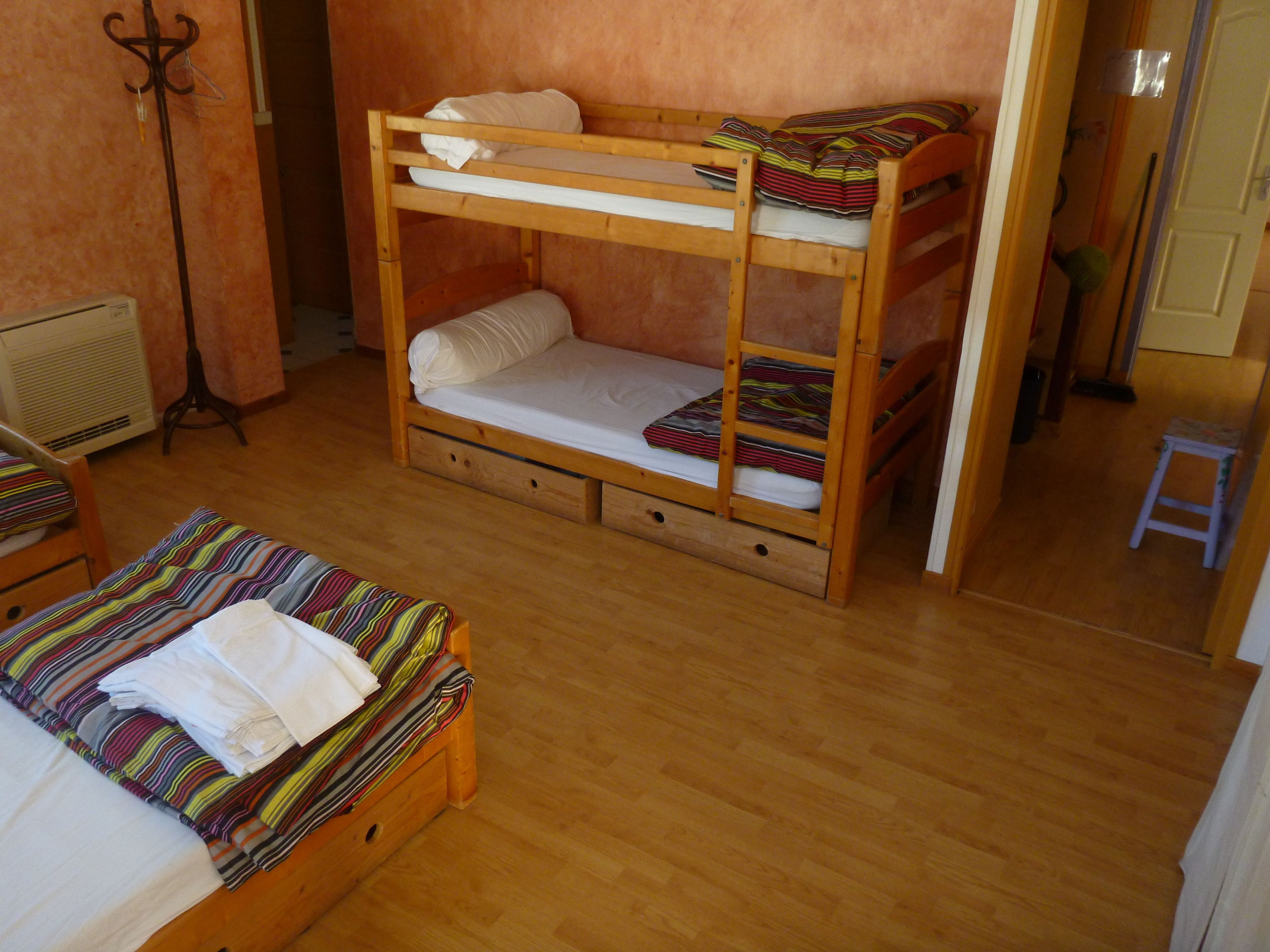 Ein Stockbett mit unterem und oberem Bett, ein kleiner Holztisch, ein Stuhl und eine Heizung.