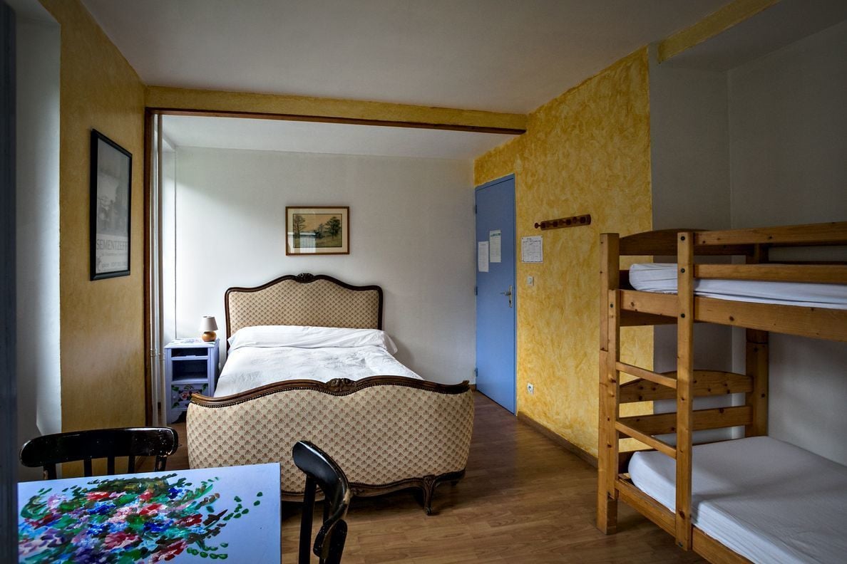 A room with a bed, bunk beds, a chair, and a desk.