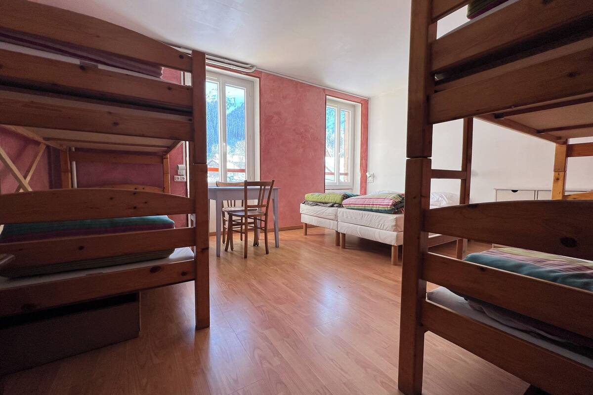 Una habitació de dormitori amb lliteres, un escriptori i una cadira.