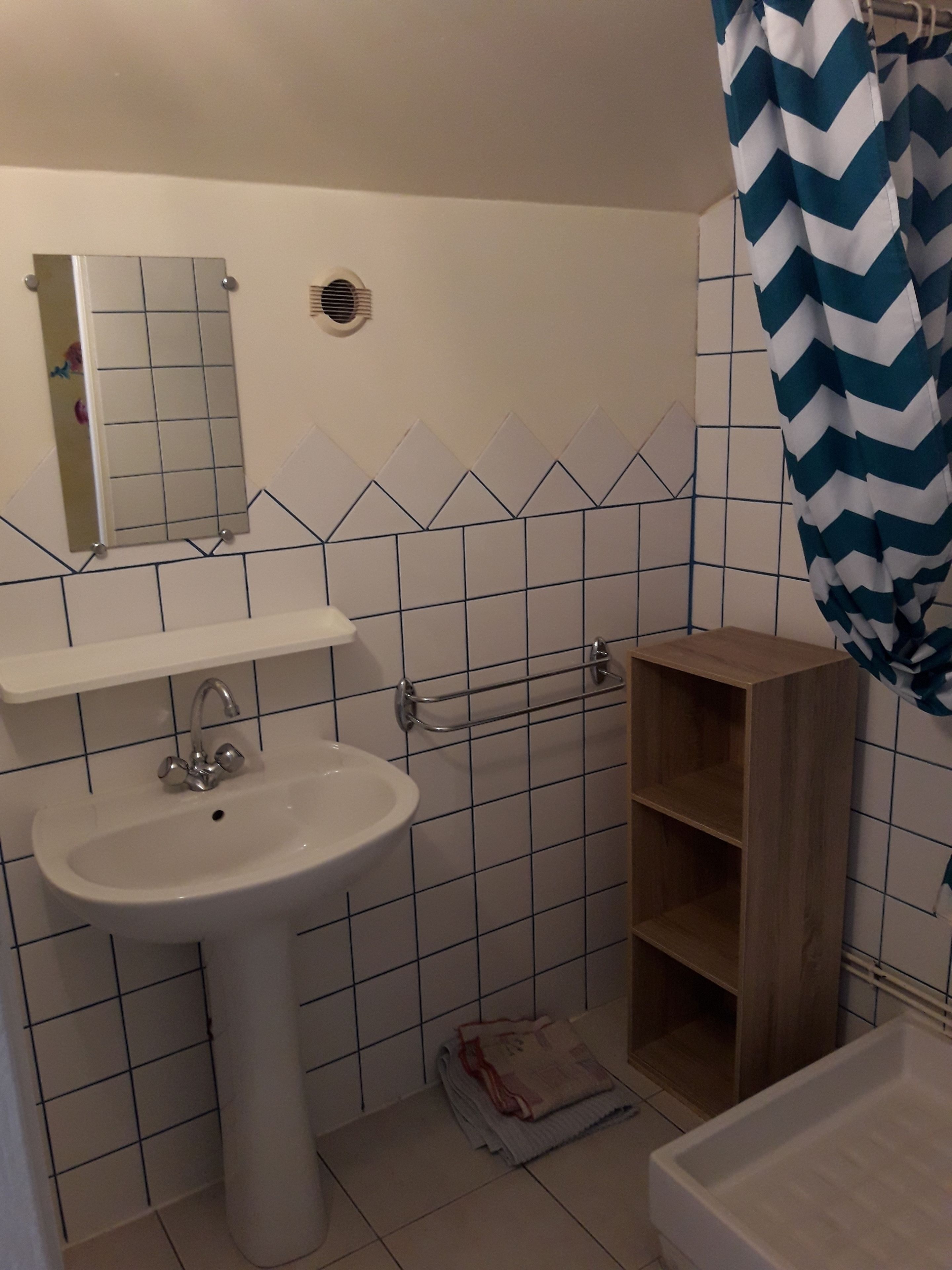 A bathroom with a white sink, mirror, and tiled walls.