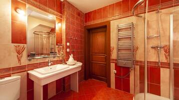 A modern bathroom with a glass shower enclosure, a white sink, and a wooden door.