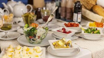 A table set with various dishes including a salad, eggs, and bread, with a teapot and bottles in the background.
