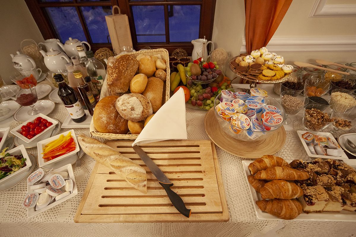 A breakfast buffet with various breads, pastries, fruits, and dairy products.