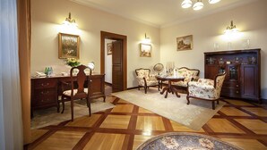 Un comedor formal con piso de madera, una mesa de comedor, sillas y una araña.
