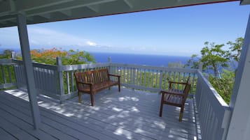 A wooden deck with two benches overlooking a scenic view of the ocean.