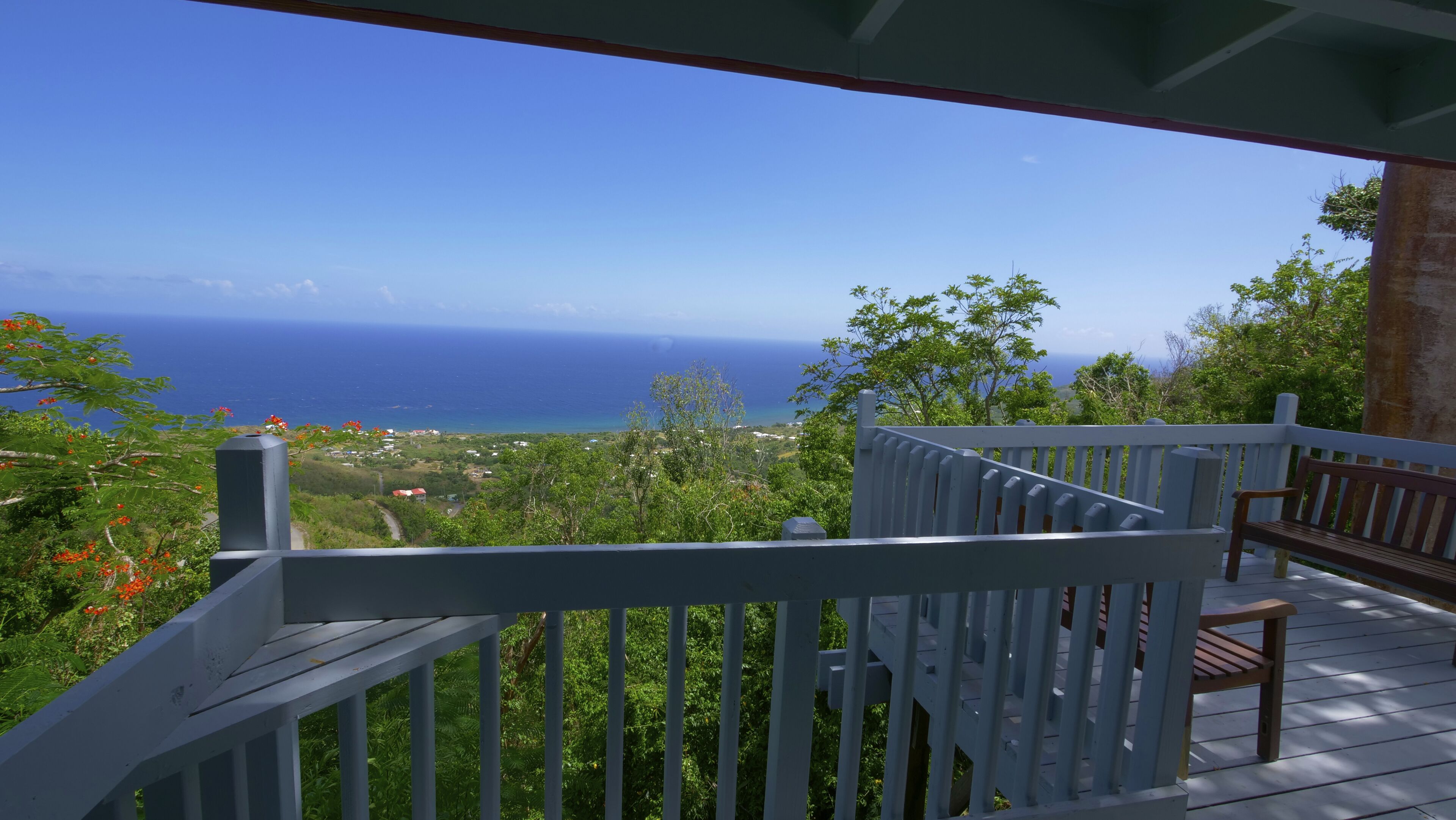 A wooden deck with a railing overlooking a coastal view.