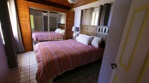 Een slaapkamer met twee bedden, houten wanden, een betegelde vloer en een spiegel.
