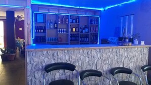 Una zona de bar con mostrador de piedra, estantes con botellas y taburetes de bar.