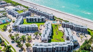 Vista aérea de un resort con varias edificaciones, una playa y una vista despejada del océano.