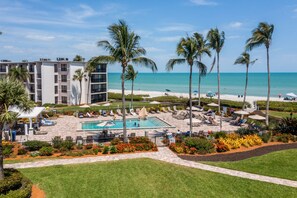 A hotel pool area with a pool, lounge chairs, and palm trees.