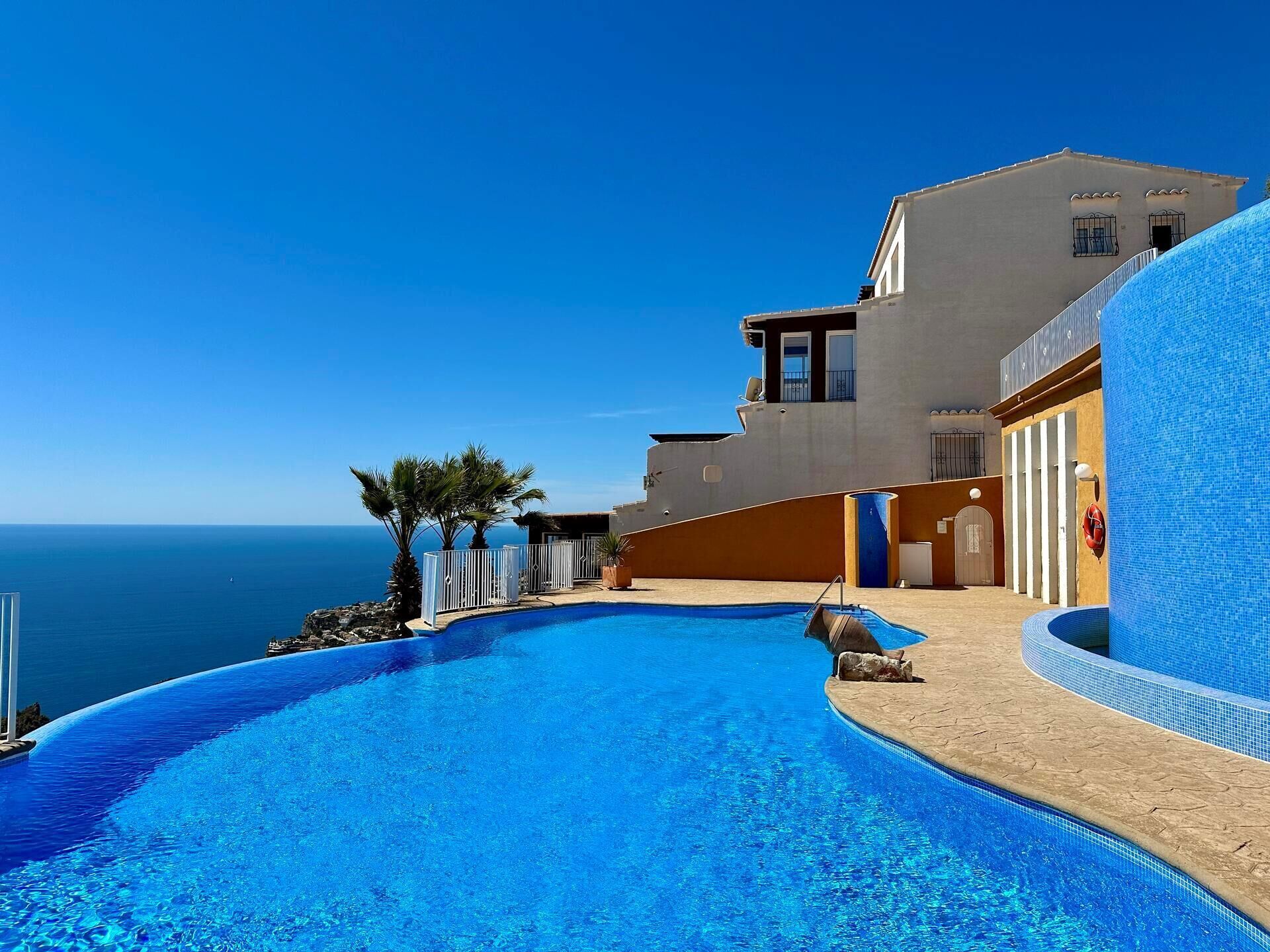 A modern hotel with a pool overlooking the sea, featuring a curved design and a clear view of the ocean.