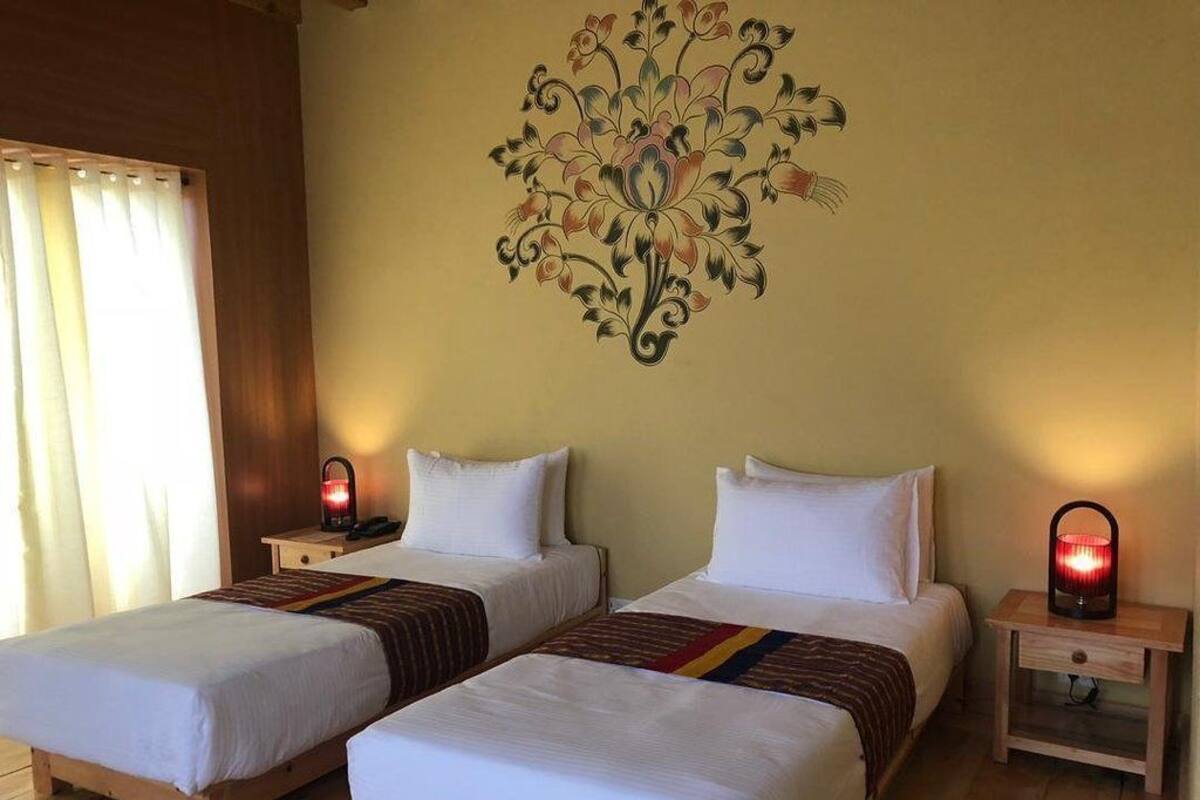 Une chambre d’hôtel avec deux lits, une fresque murale, des lampes de chevet et une fenêtre avec des rideaux.