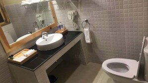 A bathroom with a sink, mirror, towel rack, and toilet. - Spirit of Bhutan Resort (Paro)