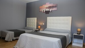 Habitación de hotel con dos camas, un cuadro grande sobre ellas y una mesita de noche con una lámpara.