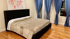 A bedroom with a bed, a headboard, a wall with a poster, and blue curtains. - MODERN Spacious 4bed 2bath HARVARD MIT BOS Cambridge Somerville walk everywhere! (Somerville)