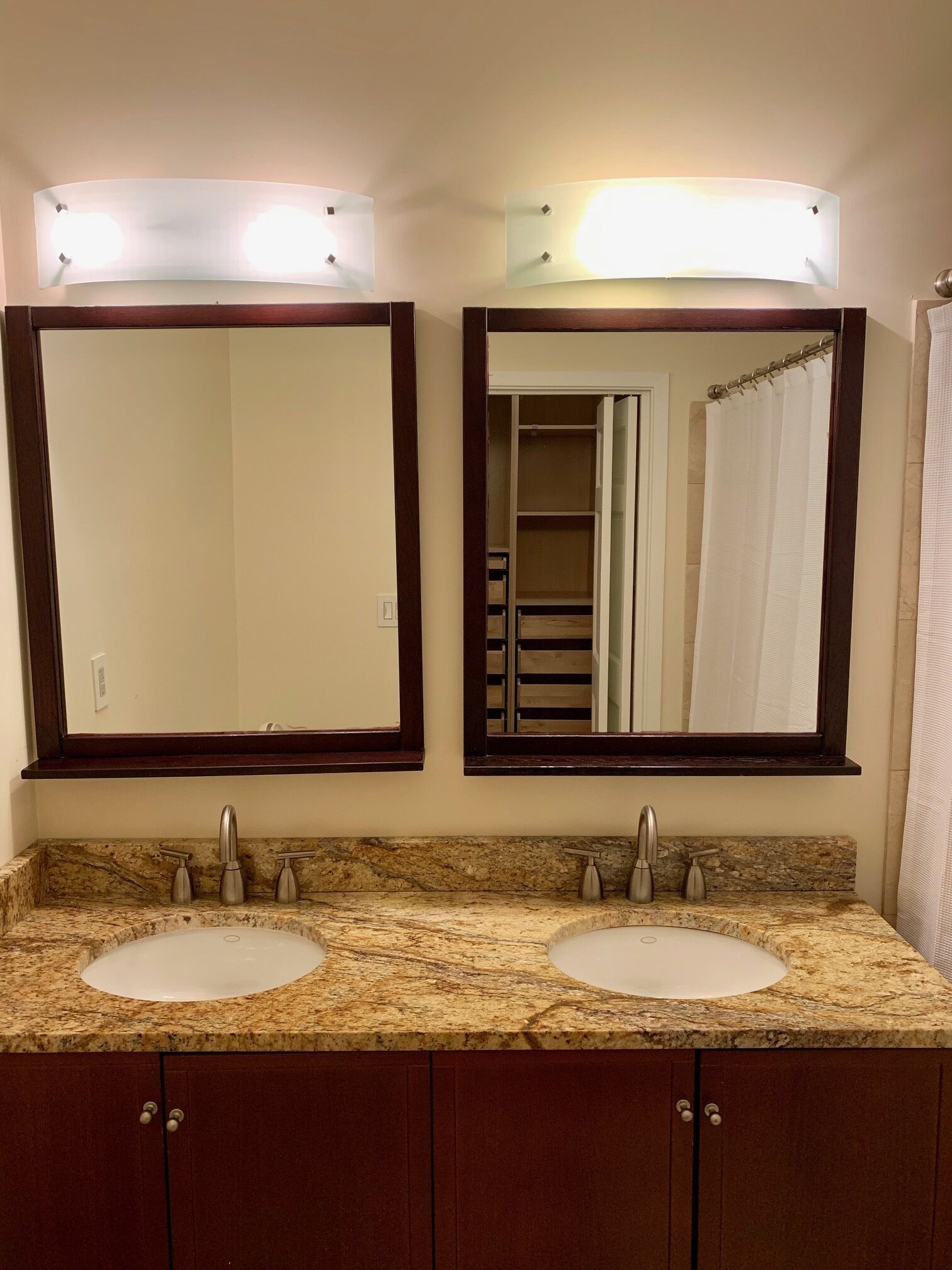 A bathroom with two sinks, a mirror, and a shower curtain.