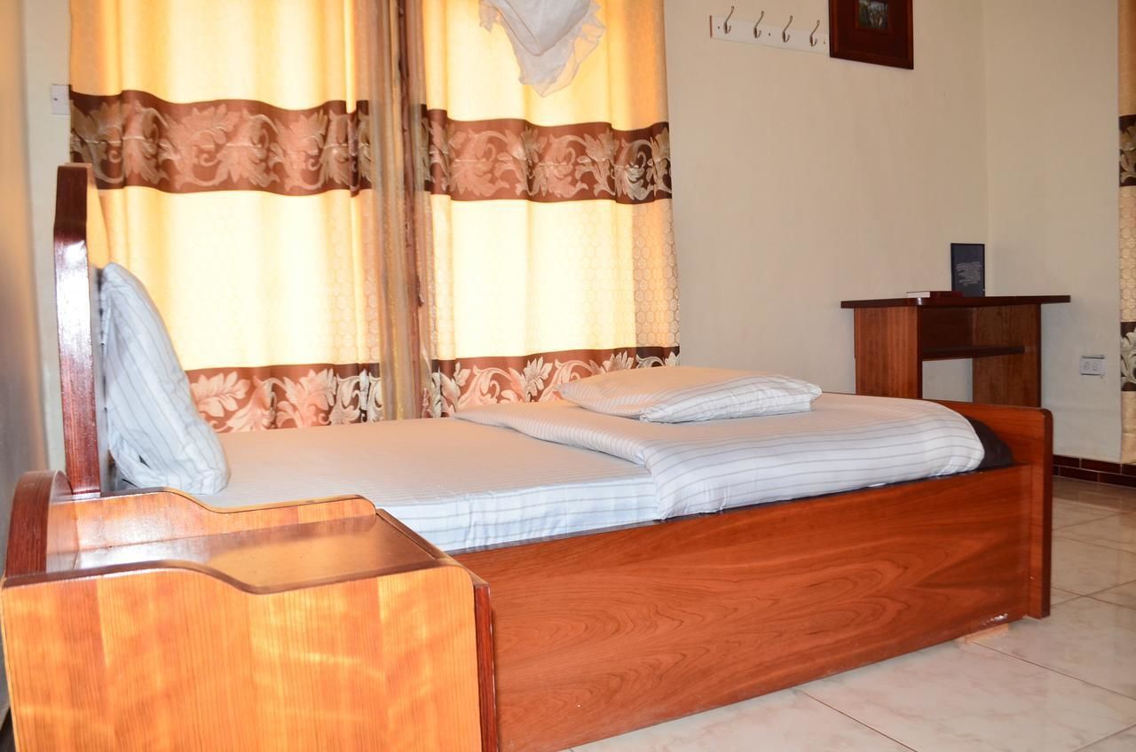 A wooden bed with a headboard, a bedside table, and curtains with a floral pattern.