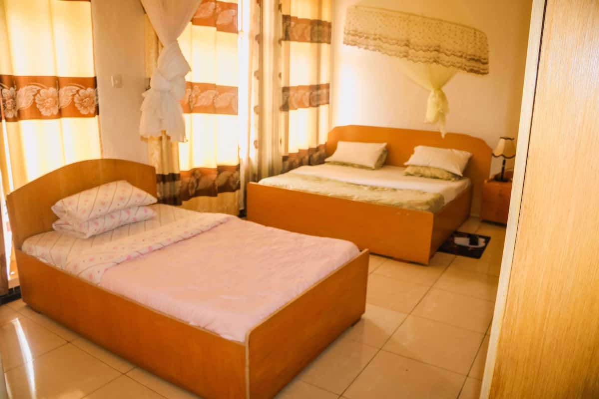 Un dormitorio con dos camas individuales, una mesita de noche y una ventana con cortinas.
