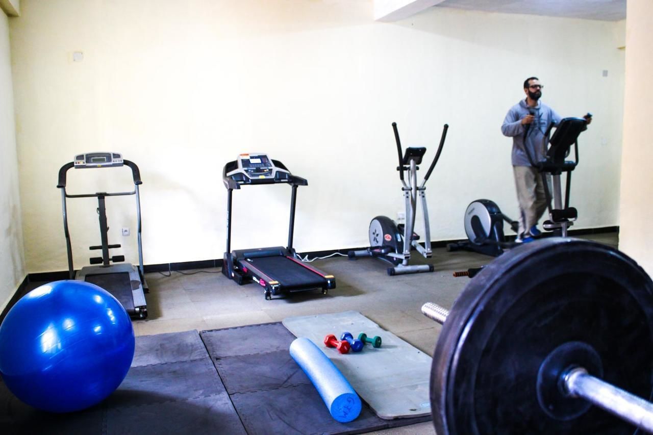 A home gym with a treadmill, elliptical, stationary bike, and weight bench.
