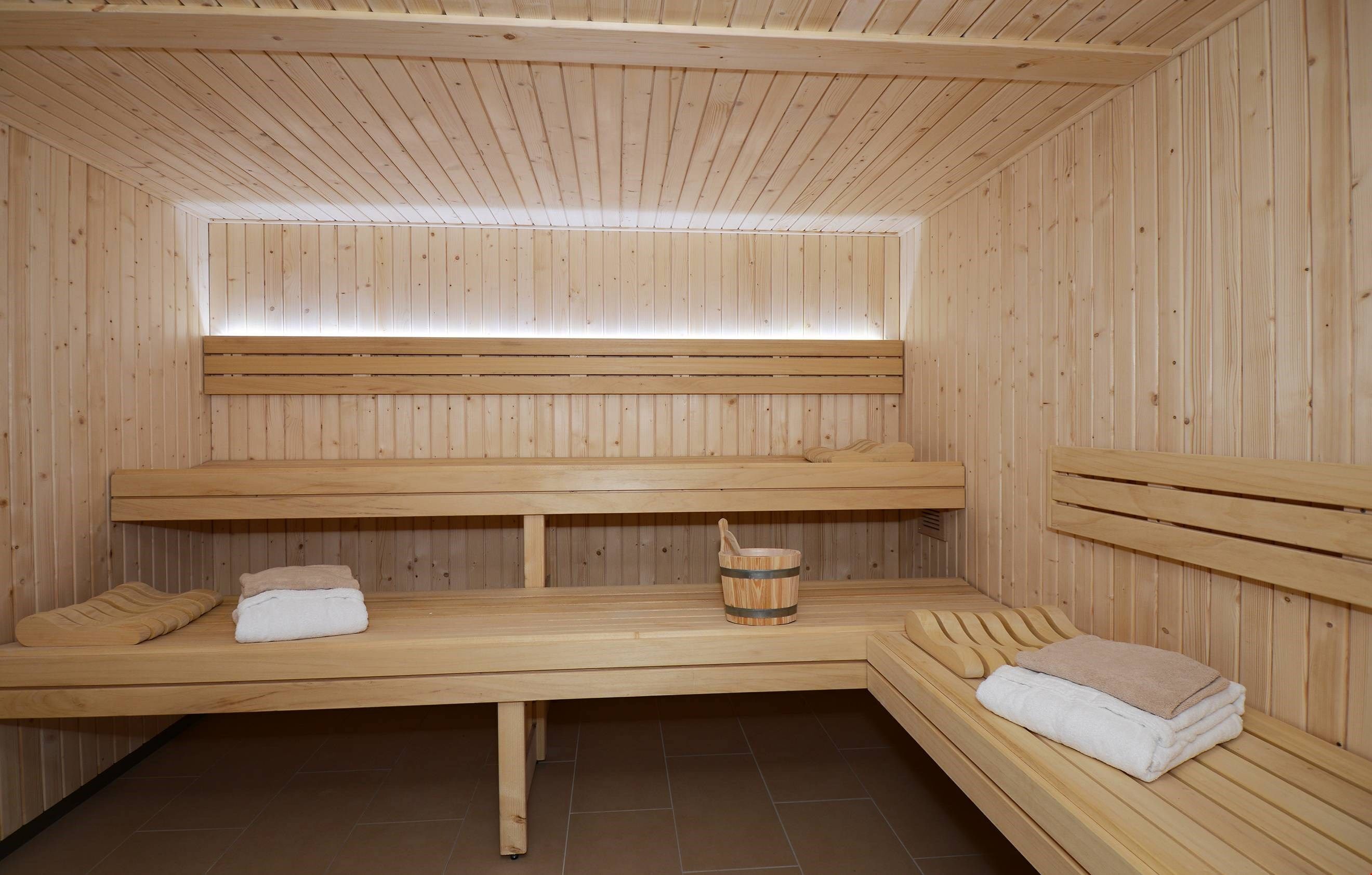 Un sauna con bancos de madera y un balde de madera.