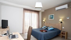 Une chambre d’hôtel équipée d’un lit, de lampes de chevet, d’un bureau avec un ordinateur portable, d’une télévision et d’un appareil de climatisation.