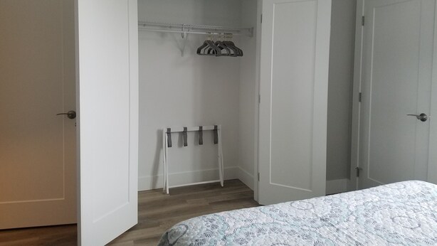 A bedroom with a bed, a closet with hanging space, and a shoe rack.