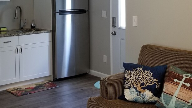 A modern kitchen with a stainless steel refrigerator, a wooden ceiling fan, and a striped sofa with decorative pillows.