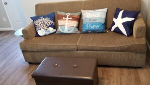 A brown sofa with striped cushions and a small brown ottoman in front.