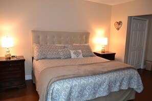 A neatly made bed with a patterned bedspread and pillows, flanked by two bedside tables with lamps, in a room with a door and a wall-mounted heart decoration. - Attractive 504 2BD Condo with Private Balcony and Jacuzzi Tub (PIGEON FORGE)