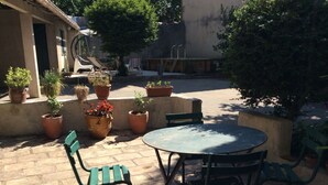 An outdoor patio with a round table and four chairs, surrounded by potted plants and a small pool. - Charming apartment with private pool and secure parking (Nîmes)