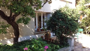 A garden area with a tree, potted plants, and a bench. - Charming apartment with private pool and secure parking (Nîmes)