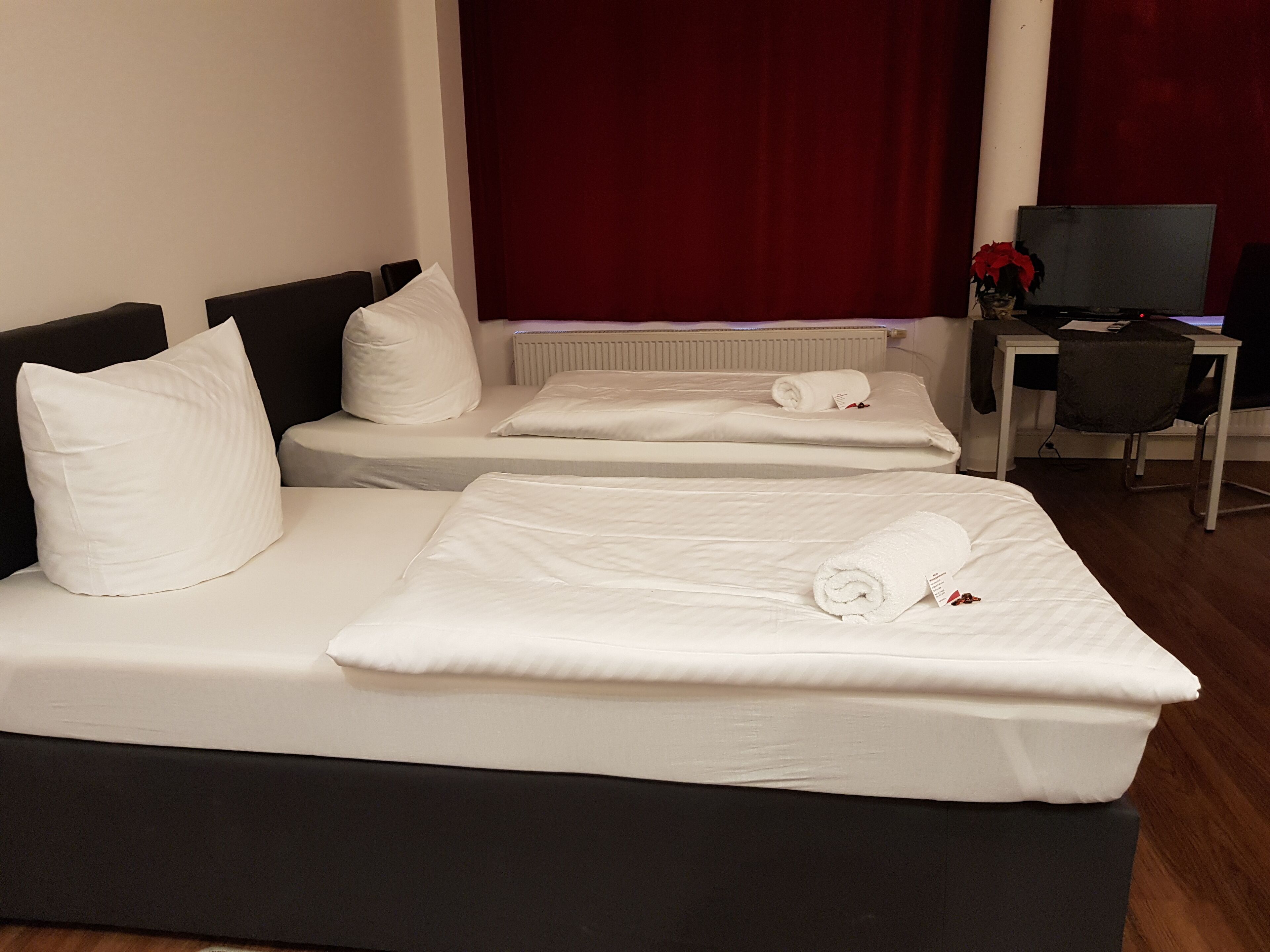 Una habitación de hotel con dos camas individuales, un escritorio con una silla y un televisor.