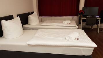 Una habitación de hotel con dos camas individuales, un escritorio con una silla y un televisor.