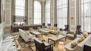 Amplia sala de estar con zona de bar, ventanas grandes y muebles clásicos.
