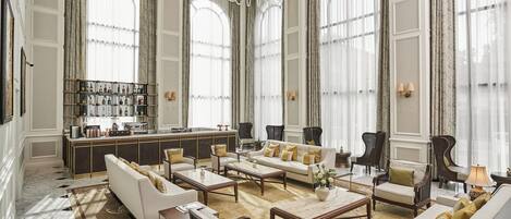 Amplia sala de estar con zona de bar, ventanas grandes y muebles clásicos.