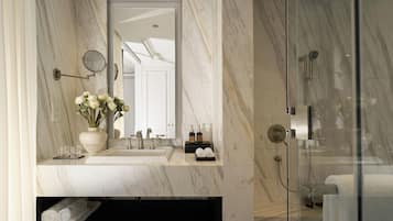 A modern bathroom with a marble sink, a mirror, a glass-enclosed shower, and a towel rack.
