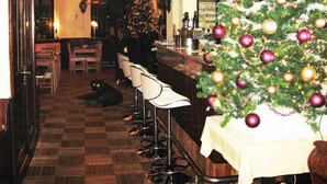 A bar area with a Christmas tree, bar stools, and a checkered floor. - Astoria Hotel Heimbach (Heimbach)