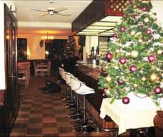 Un área de bar con un árbol de Navidad, taburetes y un suelo a cuadros.