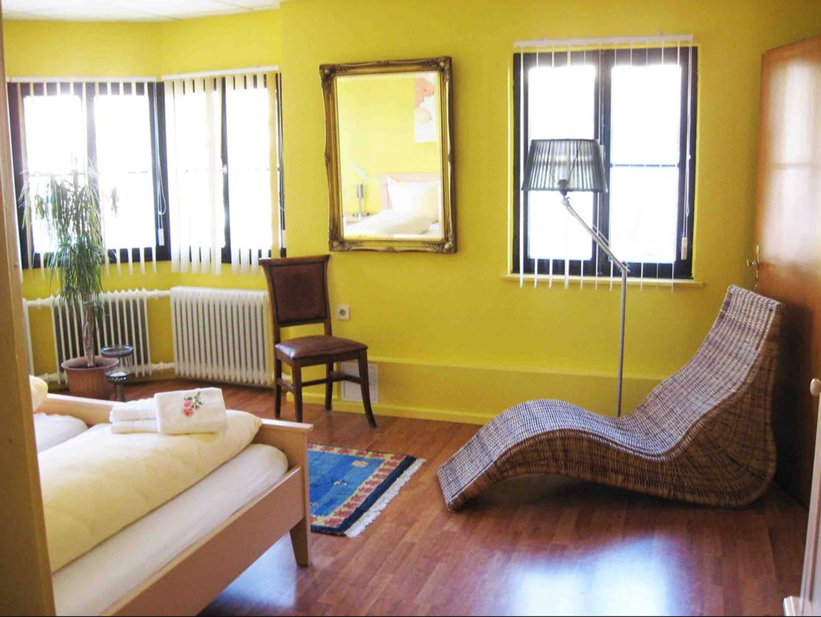 A room with a bed, a chair, a floor lamp, and a window with blinds.