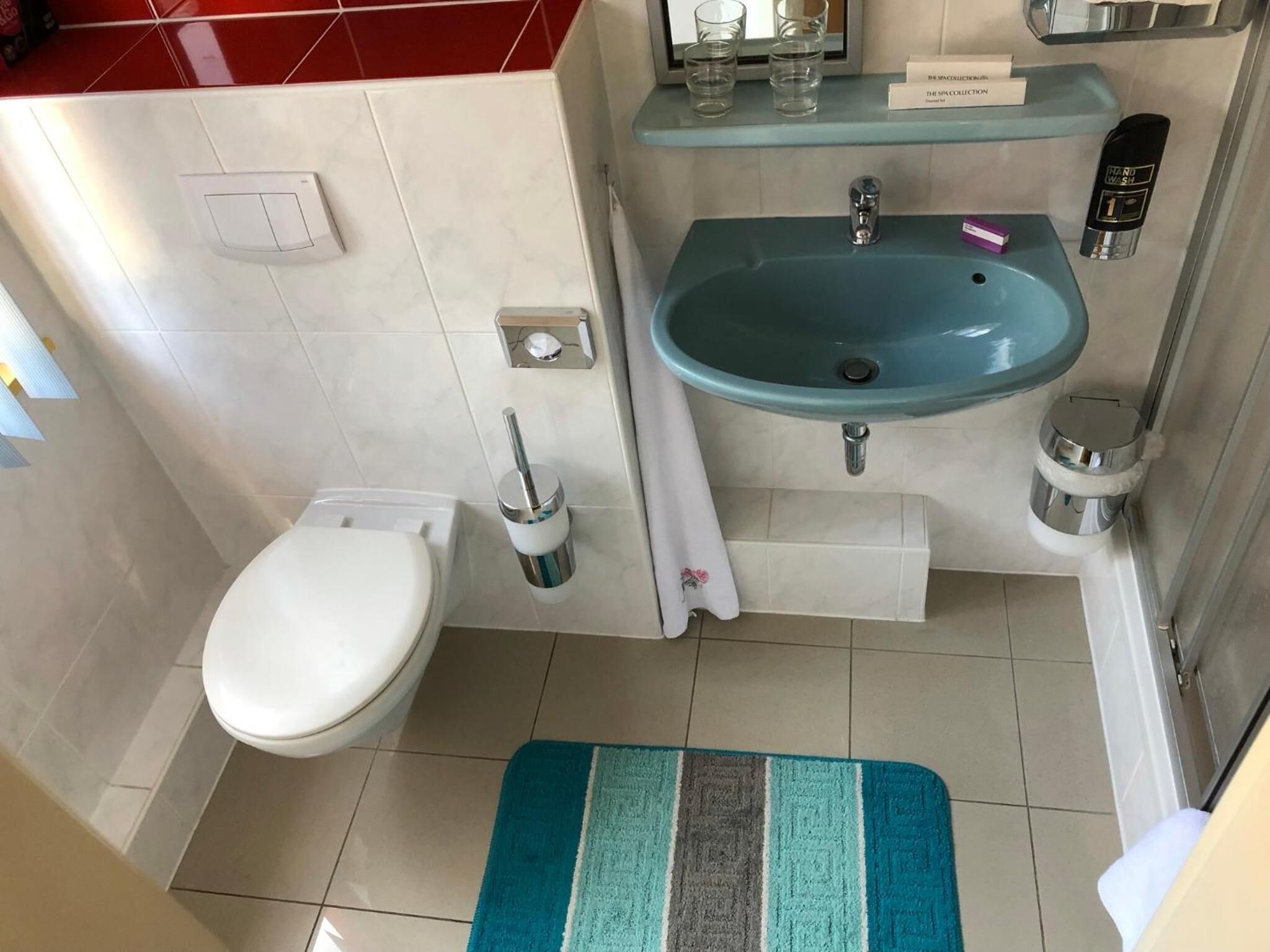 Een badkamer met toilet, wastafel en handdesinfecterend middel.