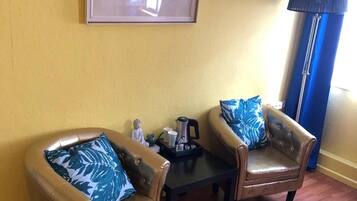 A room with two leather armchairs, a coffee table, and a framed picture on the wall.