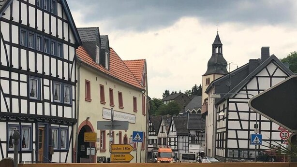 A traditional European town with half-timbered buildings, a church tower, and a café with outdoor seating. - Astoria Hotel Heimbach (Heimbach)