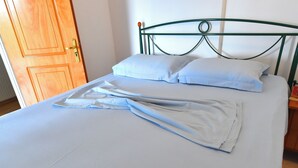 Un lit avec une tête de lit en métal, une porte en bois et un couvre-lit blanc.