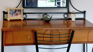 Un bureau en bois avec un miroir à cadre en métal noir, une chaise et un petit objet décoratif posé sur le bureau.