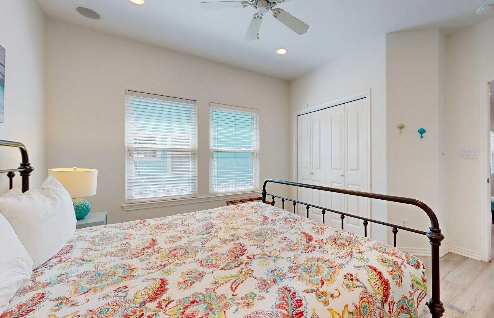 A bedroom with a bed, a nightstand, a lamp, and a window with blinds.
