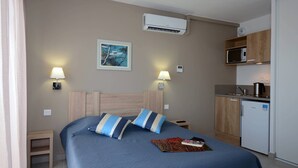 Une chambre d’hôtel équipée d’un lit, de lampes de chevet, d’un four à micro-ondes, d’un réfrigérateur et d’un appareil de climatisation.